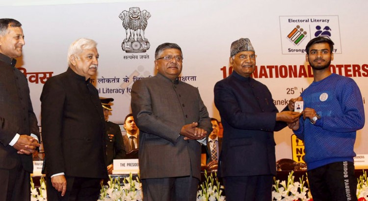 ram nath kovind giving away the electoral photo identity card to one of the new voters